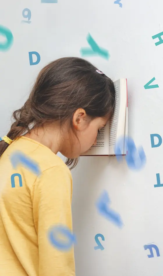Fillette le front appuyé contre un livre ouvert, entourée de lettres flottantes